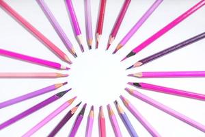 pink and purple pencils lined up in a circle on a white background. photo with round frame for copy space