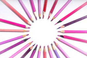 pink and purple pencils close up lined up in a circle on a white background. photo with round frame for copy space