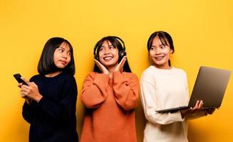dos asiático mujer trabajando en ordenador portátil y teléfono. a el mismo hora dos de ellos fueron comunicado en línea y demostración contento sonrisas y escucha a música alrededor personas y amigos en línea comunicación