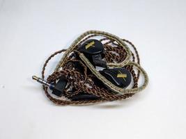A black in ear monitor or IEM with brown cable and white background photo