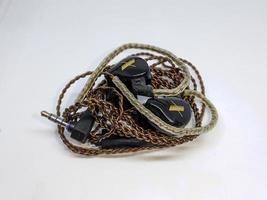 A black in ear monitor or IEM with brown cable and white background photo