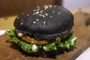 foto de el negro hamburguesa en de madera cortar tablero es muy adecuado para un rápido comida menú