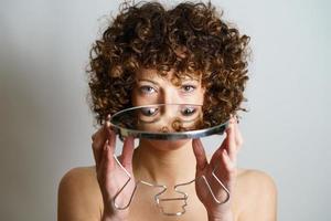 Adult female with curly hair holding mirror in hands with reflection of eyes photo