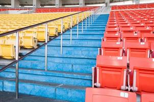 Empty orange and yellow seats at stadium,Rows walkway of seat on a soccer stadium photo