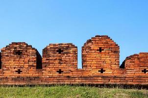 A portion of the ancient fortified city wall built of brick with cross bow cutouts and crenelations photo