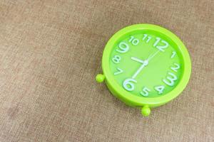 Green alarm clock on brown sackcloth background show half eight o'clock or 8.30 a.m. photo