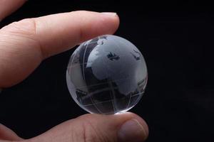 cristal de globo terráqueo en la mano. economía y negocios globales. concepto ambiental o ecológico foto