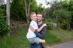 el chico en de papá brazos mira a el cámara y sonrisas foto