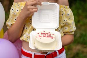 un abierto caja con un bento pastel para un cumpleaños en el manos de un persona foto