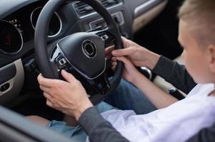 Dad and a cute boy hold the steering wheel of a car with their hands photo