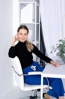 The girl works in a white office with a laptop and flowers on the table photo