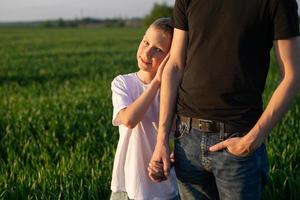 A cute child holds his father's hand and snuggles up to her. Nature walk photo