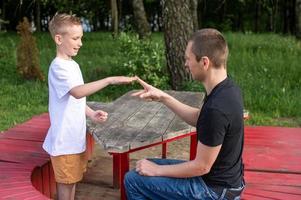 A cute boy is playing a game with his dad. shows signs with his hands photo