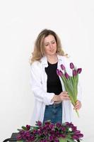 A cute girl collected a bouquet of purple tulips. Stands on a white background photo