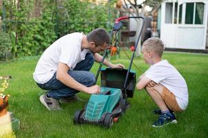 Dad and his curious son mow the lawn. Disassemble the lawn mower photo