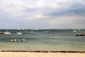 Many sailboats on a sandy beach in Germany with some beach chairs. photo