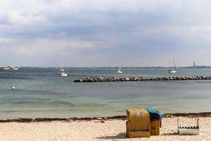 Many sailboats on a sandy beach in Germany with some beach chairs. photo