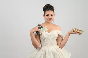 Young asian beautiful bride posting with smartphone and banknote in hand photo