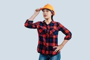 Young female engineer in helmet stand with thoughtful posture photo