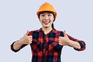 Young female engineer in helmet stand with thumb up posture photo