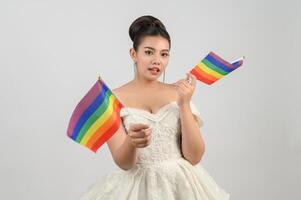 Young asian beautiful bride with rainbow flag on white background photo