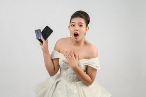 Young asian beautiful bride posting with credit card and smartphone in hand photo