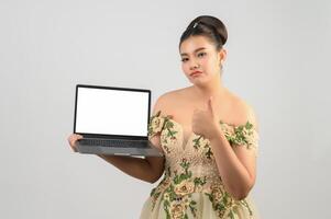 Una joven novia asiática hermosa posa con una computadora portátil simulada en la mano foto