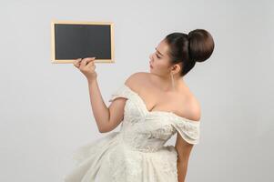 Young asian beautiful bride pose with blank blackboard in hand photo