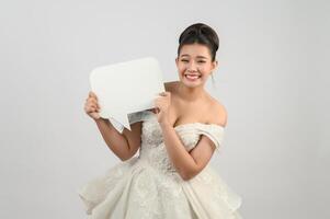 joven asiática hermosa novia posa con pancarta de maqueta en la mano foto