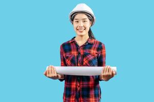 Young female engineer wearing white safety helmet with Blueprints photo