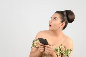 joven novia asiática hermosa que publica con un teléfono inteligente en la mano foto