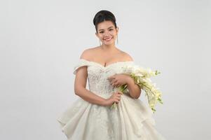 Young asian beautiful bride with orchid bouquet on white background photo