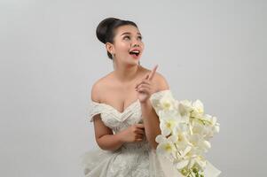 Hermosa novia asiática joven señalar con el dedo feliz sobre fondo blanco. foto
