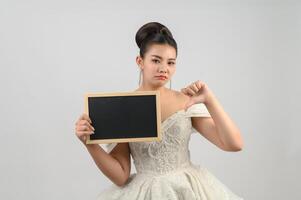 Young asian beautiful bride pose with blank blackboard in hand photo