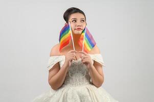 joven novia hermosa asiática con la bandera del arco iris sobre fondo blanco foto