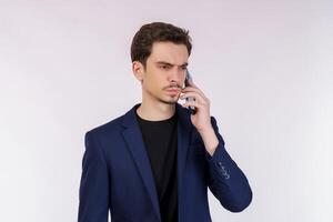 Portrait of unsatisfied handsome businessman talking by mobile phone and standing isolated over white background photo