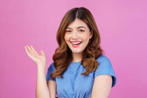 Portrait of happy young woman wearing casual t-shirt waving hands isolated over pink background photo