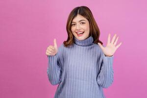 Portrait of Happy young woman pointing up with finger number six isolated over pink background photo