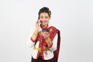 Portrait of Beautiful Thai Woman in Traditional Clothing Posing with smartphone and credit card photo