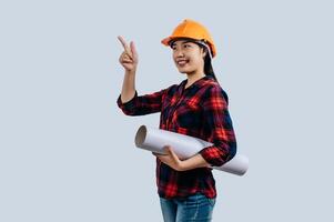 Young female engineer wearing a yellow safety helmet with Blueprints photo