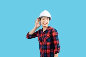 Young female engineer hand over ear to making hear gesture photo