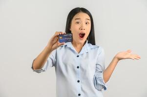 retrato de una joven asiática positiva que muestra un salario de buen humor con tarjeta de crédito aislado de fondo blanco foto