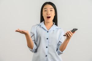 Portrait of Young asian woman expressing surprise while using mobile phone isolated over white background photo