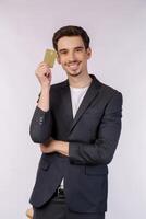 Portrait of Young smiling handsome businessman showing credit card isolated over white background photo