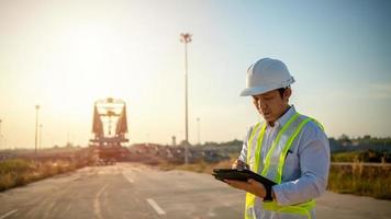 Asian engineer with hardhat using tablet pc computer inspecting and working at construction site photo