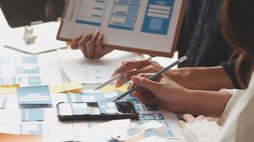 Close up ux developer and ui designer brainstorming about mobile app interface wireframe design on table with customer breif and color code at modern office.Creative digital development agency video