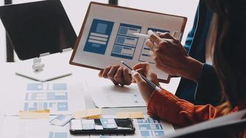 Close up ux developer and ui designer brainstorming about mobile app interface wireframe design on table with customer breif and color code at modern office.Creative digital development agency video