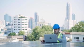 ecológico engenheiro usando computador portátil e inspecionar sobre solar painéis em cobertura topo do Alto prédio. video
