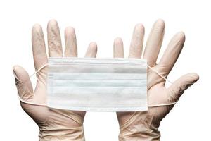 Human hands holding surgery medical face mask in white gloves isolated on white background. Medicinal concept during pandemic and coronavirus photo