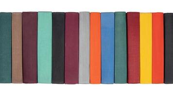Stack of old hardcover books on bookshelf. Close up view of multicolored vintage hardback books - black, brown, purple, turquoise, gray, orange, blue, green, red, yellow. Isolated on white background